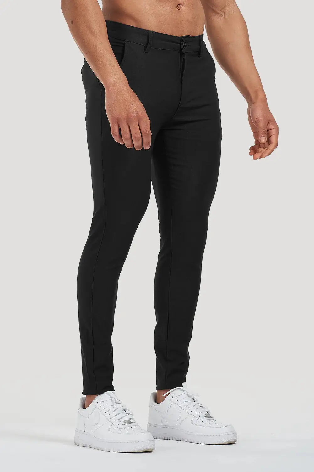 Side view of Avari Trousers Black, highlighting the slim-fit tapered cut and modern styling paired with white sneakers.