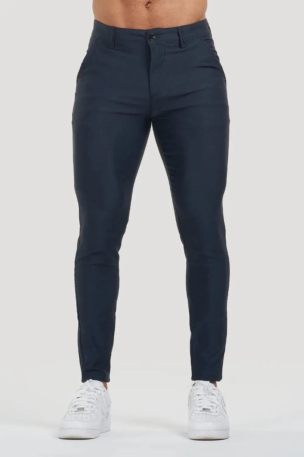 Front view of Avari Trousers in dark blue, showcasing the sleek slim-fit design paired with white sneakers.