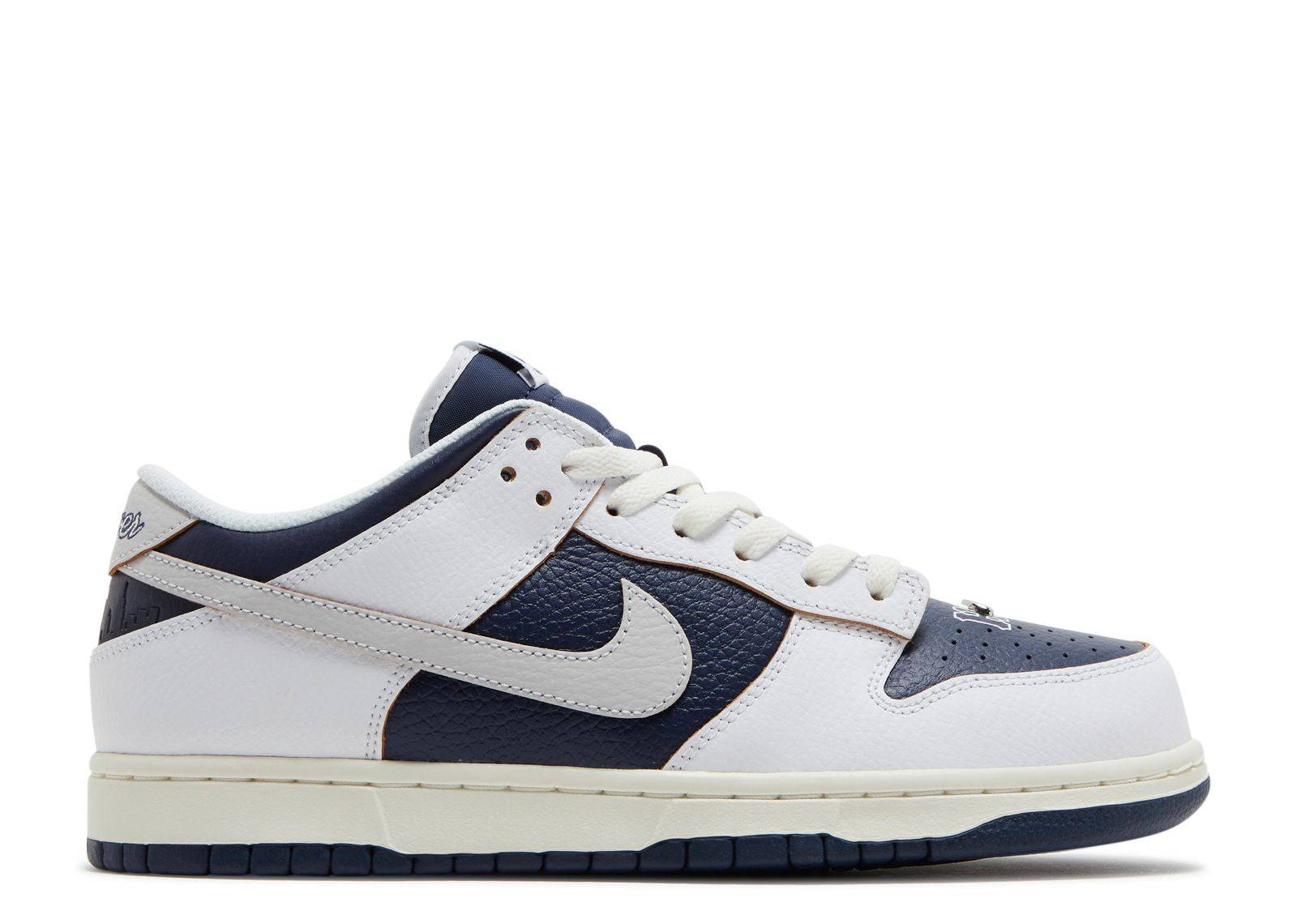 HUF x Dunk Low SB New York sneaker featuring a white and navy leather upper, Nike Swoosh, and glow-in-the-dark outsole. Celebrates HUF's 20th anniversary.