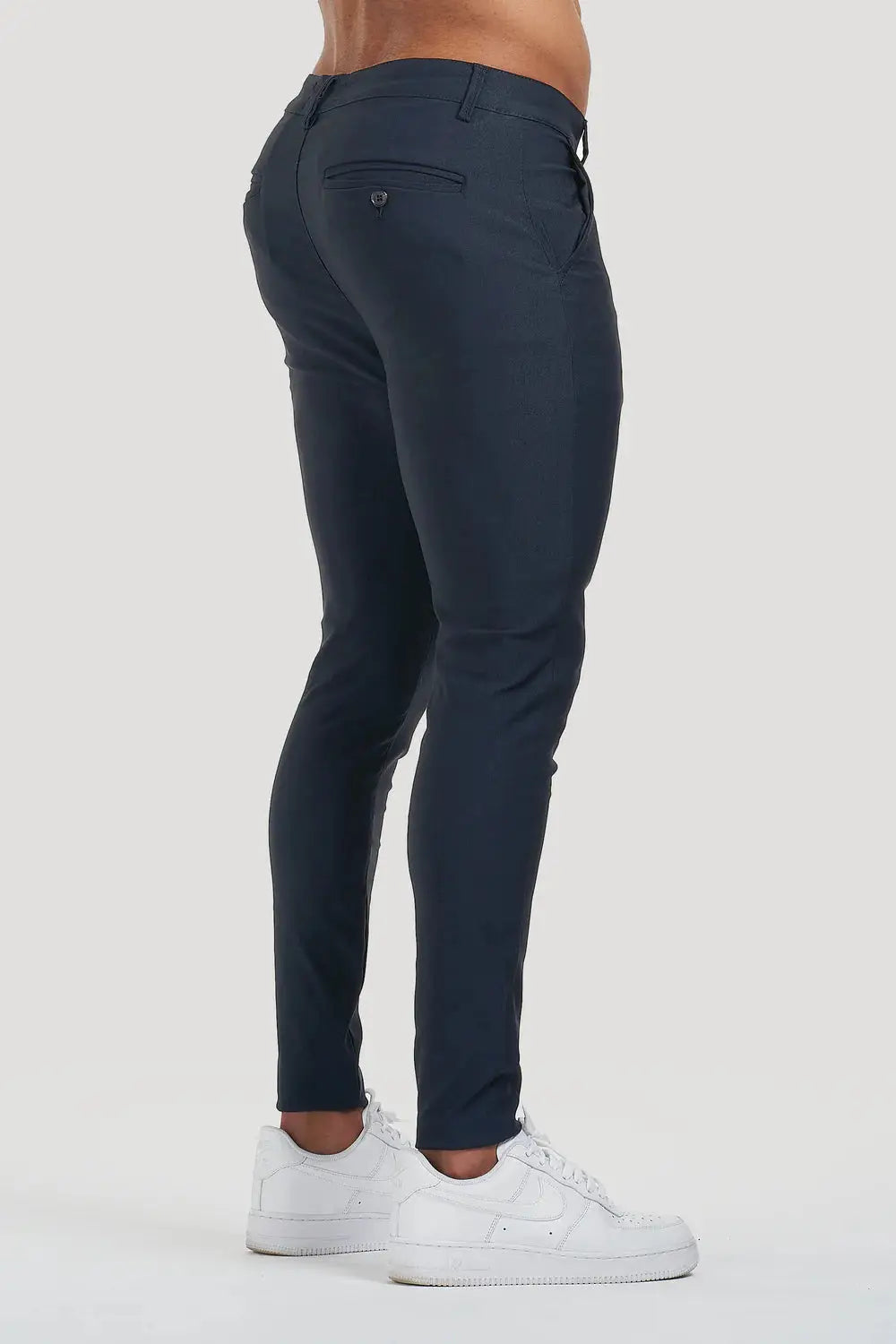 Angled side view of Avari Trousers in dark blue, highlighting the tapered ankle and back pocket details.