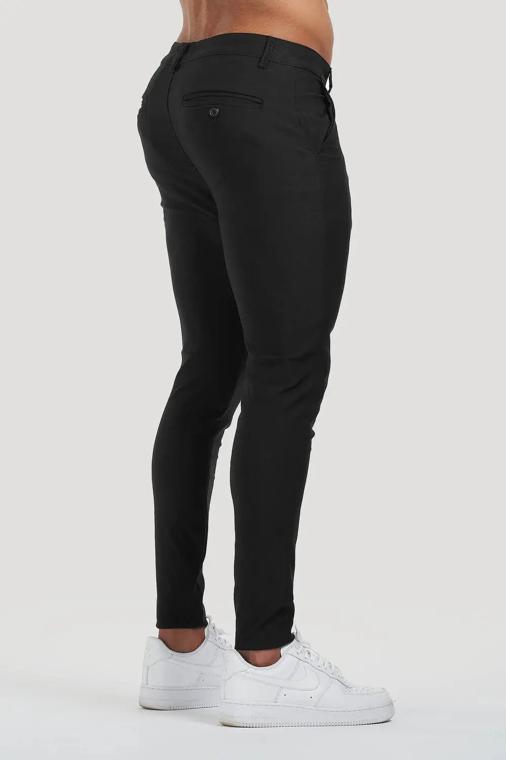 Side-back view of Avari Trousers Black, emphasizing the tapered fit and buttoned back pocket details.