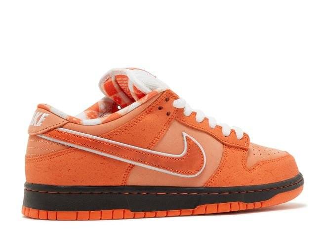 Side view of Concepts x Dunk Low SB Orange Lobster sneaker with orange suede, white Nike Swoosh, and bib-pattern lining for a bold design.