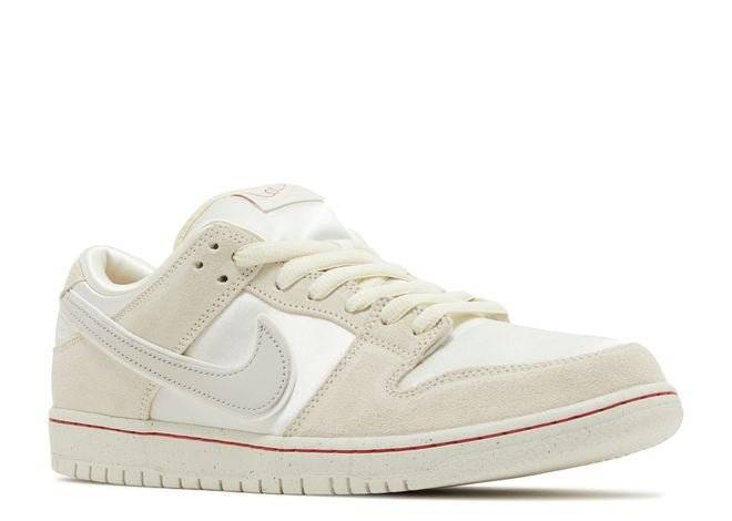 Nike Dunk Low City of Love sneaker showcasing light bone suede and leather upper with red detailing, angled front view.