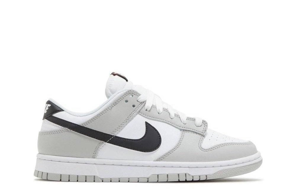 Nike Dunk Low SE Lottery Pack Grey Fog sneaker featuring a white leather upper with grey overlays and a black Swoosh logo. Perfect for casual wear.