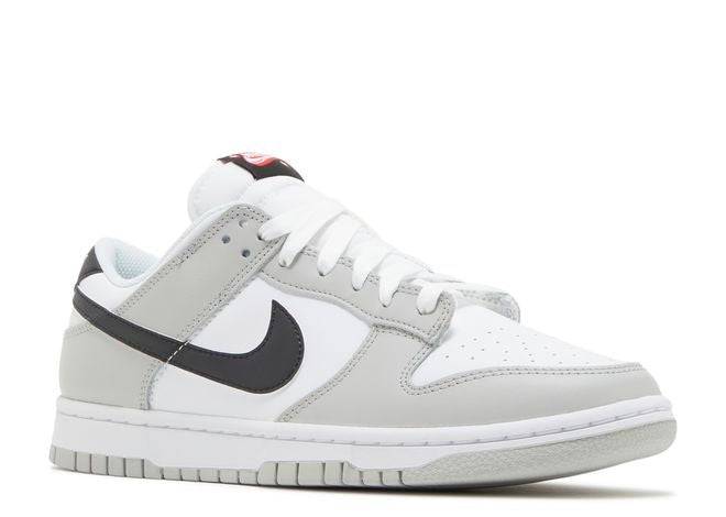 Side angle of the Nike Dunk Low SE Lottery Pack Grey Fog sneaker showcasing its sleek design, white leather base, and grey accents.