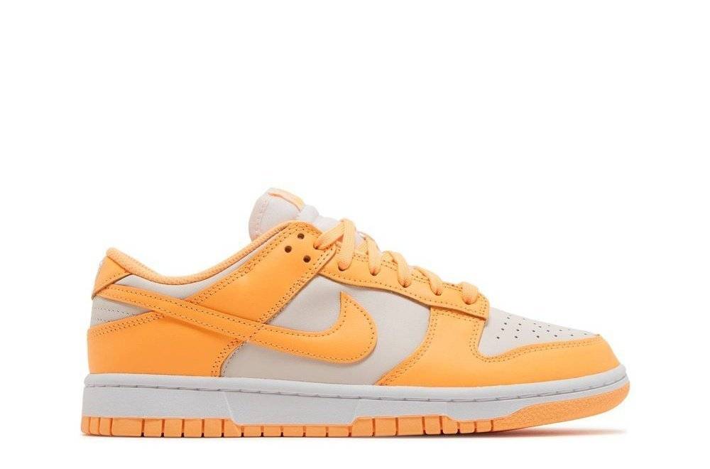 Wmns Dunk Low Peach Cream sneaker featuring a peach cream and white leather upper, Nike Swoosh logo, cushioned midsole, and perforated toe design.